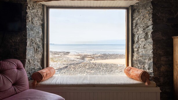 Ein Zimmer mit Stehwänden und einem Fenster mit Blick auf einen Strand.