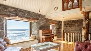 Ein gemütliches Wohnzimmer mit einem Klavier, einem Glastisch und Blick auf den Ozean.