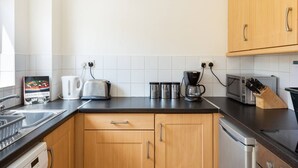 A kitchen with wooden cabinets, a toaster, a kettle, a coffee maker, and a microwave. - Dough Beag 10 (250m to Lahinch Beach), Dough Beag Apartment (Lahinch)