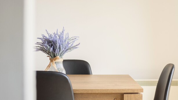 A dining area with a wooden table and black chairs, a vase with flowers, and a cityscape painting on the wall. - Dough Beag 10 (250m to Lahinch Beach), Dough Beag Apartment (Lahinch)
