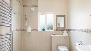 Une salle de bain équipée d’une douche, de toilettes, d’un lavabo et d’un miroir.