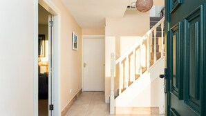 Un couloir avec un escalier menant à une porte.