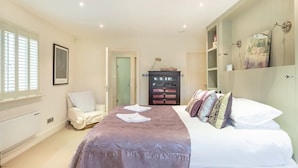 A bedroom with a bed, a chair, a wardrobe, and a shelf with decorative items. - Shutters - Lovely family home!, Shutters (Lahinch)