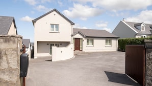 A residential area with houses, a driveway, and a stone wall. - Shutters - Lovely family home!, Shutters (Lahinch)
