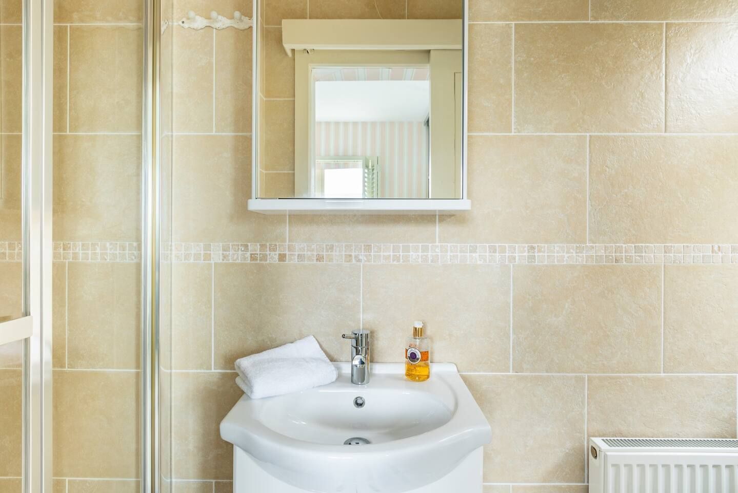 A bathroom with a white sink, a mirror above it, and a towel on the sink.