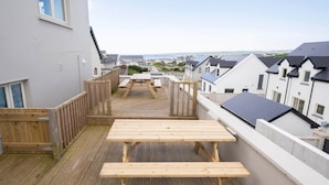 A wooden deck with picnic tables and a view of the sea and neighboring houses. - Shutters - Lovely family home!, Shutters (Lahinch)