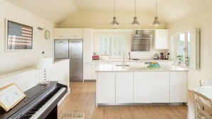A modern kitchen with a piano, a refrigerator, and pendant lights. - Shutters - Lovely family home!, Shutters (Lahinch)