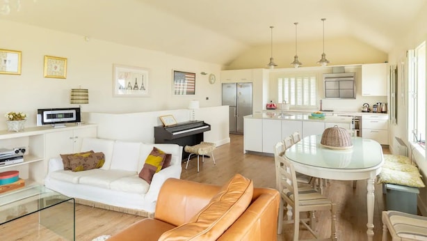 A spacious living area with a white sofa, a brown leather couch, a glass dining table, and a kitchen in the background. - Shutters - Lovely family home!, Shutters (Lahinch)