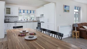 Eine moderne Küche mit weißen Schränken, einem Holzespeisetisch und einem braunen Ledersofa.