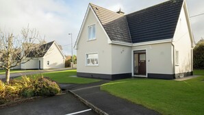 A two-story residential house with a dark roof, white exterior walls, and a front door. - The Links 08, Amazing Location- Food, Drinks, Surf, & Golf! - 8 (Lahinch)