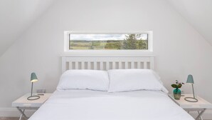 A bedroom with a bed, a window with a view of a landscape, and two bedside tables with lamps. - The Play School, The Play School (Miltown Malbay)