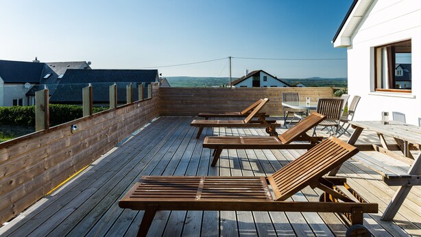 Una terraza de madera con bancos y mesas, con vistas a un paisaje pintoresco.