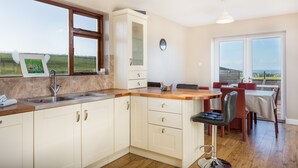 Una cocina con encimera de madera, un lavabo y una zona de comedor con una mesa y sillas.