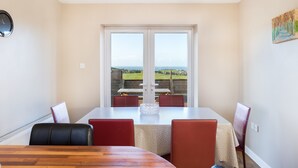 Un comedor con una mesa y sillas, un reloj en la pared y vistas al exterior.