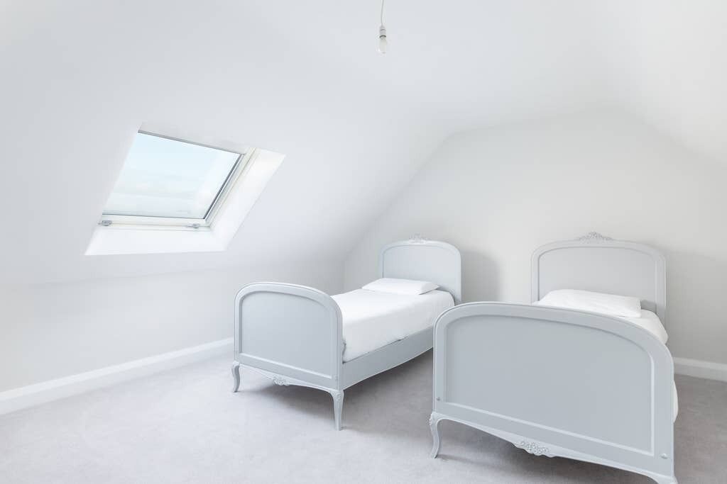 A small, white, attic-style bedroom with two single beds and a skylight.