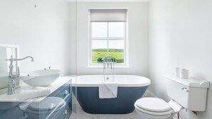 Ein modernes Badezimmer mit einer freistehenden Badewanne, einem Waschbecken und einer Toilette.