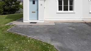 A two-story house with a light blue front door, a small porch, and a driveway leading to the entrance. - Summer Cove 10 (900m to Lahinch Beach) (Lahinch)