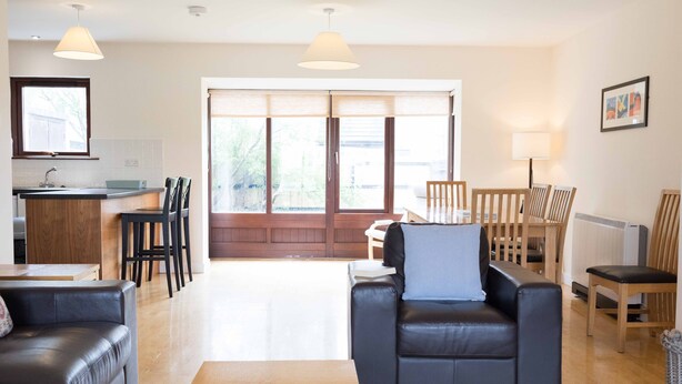 Una sala moderna con un sofá, una mesa de centro y una zona de comedor con sillas y una mesa.
