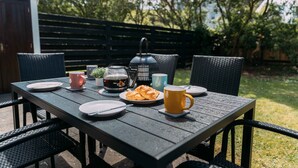 Una mesa de madera al aire libre con platos, tazas, una tetera y un farol.