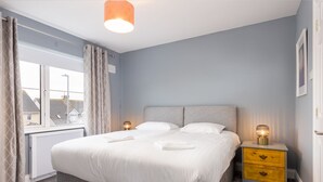 Une chambre à coucher avec un lit, des tables de chevet, une fenêtre et un radiateur.