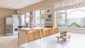 Een compacte keuken met een ingebouwde wasmachine, een koelkast en een eethoek met een tafel en stoelen.