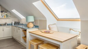 Une cuisine moderne dotée de fenêtres de toit, d’une table à manger en bois et offrant une vue sur le ciel.