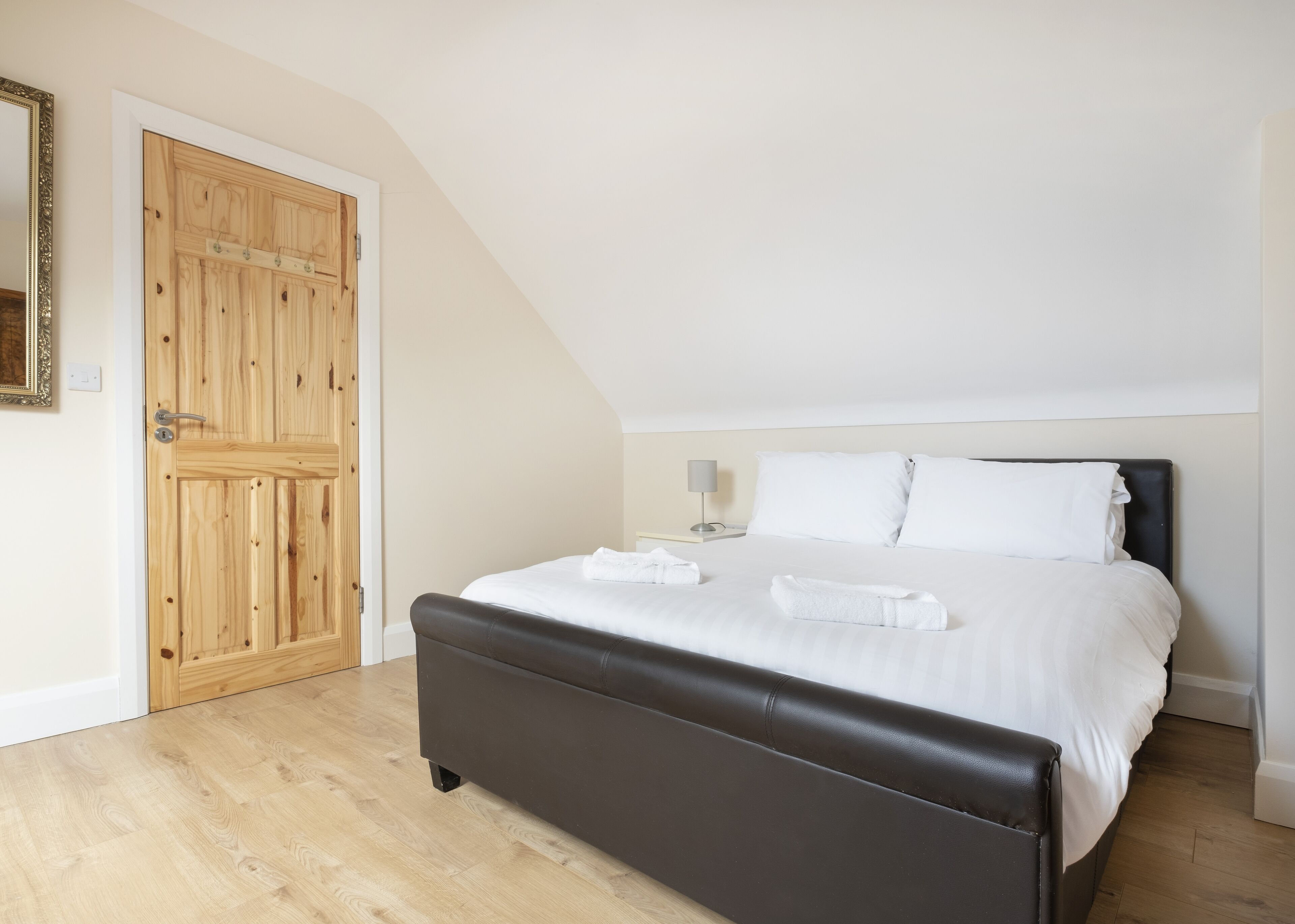 Una camera da letto con un letto grande, una porta in legno e un soffitto a falde.