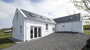Ein weißes Gebäude mit geneigtem Dach und vielen Fenstern.