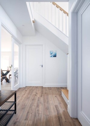A spacious hallway with wooden flooring, white walls, and a staircase with wooden railings. - Cill Stuifin 15 - Beach Vibes! (Lahinch)