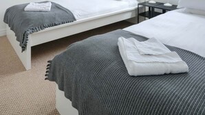 A modern bedroom with two beds, a large window, and a view of the outside. - Clochan Na Mara 15 (In Liscannor Village) (County Clare)