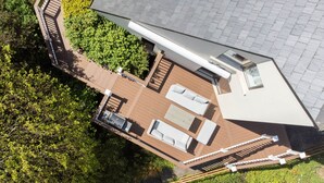 Vue aérienne d’une maison moderne dotée d’une terrasse, d’un espace salon extérieur et d’une grande fenêtre.