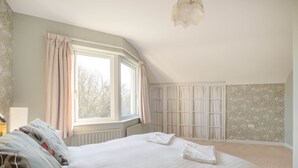 Une chambre avec un grand lit, une fenêtre avec des rideaux, un radiateur et une armoire.