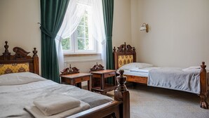 A room with two wooden beds, a small wooden desk, a radiator, and a window with curtains. - Zielony Kompleks Dwór Ostoya (Trzebownisko)