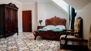 A bedroom with a large bed, a wooden wardrobe, a chair, and a patterned floor. - Zielony Kompleks Dwór Ostoya (Trzebownisko)
