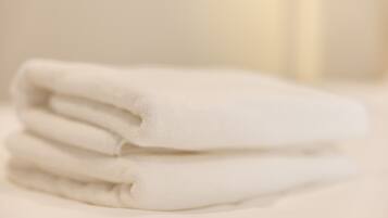 A stack of white towels on a bed.