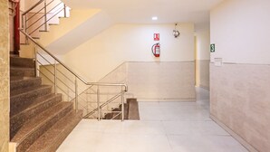 Un escalier propre et bien éclairé, équipé d’un extincteur et d’une plaque indiquant le numéro de l’étage sur le mur.