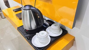 Une machine à café avec deux tasses posées sur un plateau, une télécommande et un comptoir jaune.