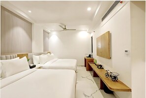 Une chambre d’hôtel moderne avec deux lits, un banc en bois, un vélo et un miroir au mur.