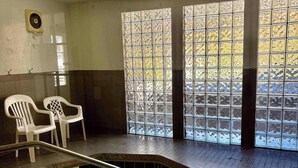 Une piscine intérieure à l’eau claire, dont la profondeur est indiquée par un repère à 3 pieds, et qui offre une vue sur l’extérieur à travers une fenêtre en verre décoratif.