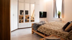 A bedroom with a bed, a TV, a window with curtains, and a wardrobe. - NEU Luxus-apartment! Wasserbett-terrasse-smarttv (Magdeburg)