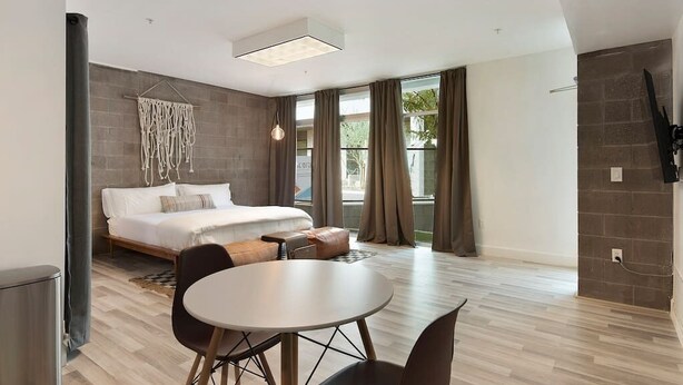 Una habitación de hotel moderna con una cama, una mesa de comedor y un televisor.