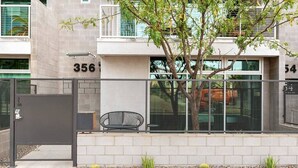 Un edificio moderno con entrada protegida, unidades numeradas y un pequeño espacio de estar con una silla y una mesa.