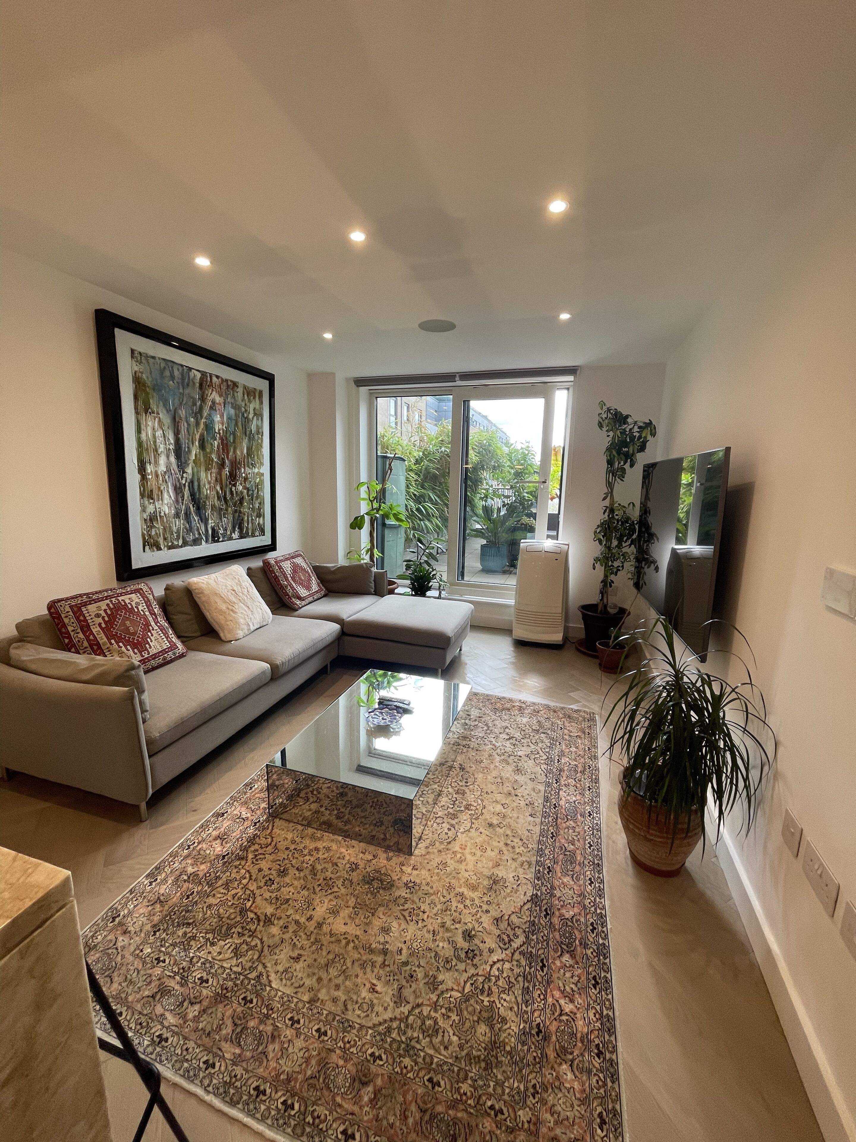 A modern living room with a sectional sofa, a glass coffee table, and a large abstract painting.
