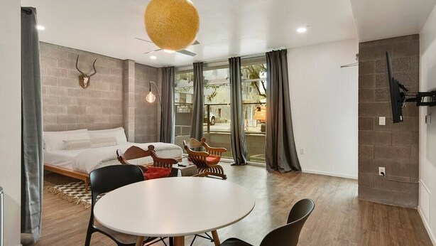 A modern room with a bed, a round dining table, and a ceiling fan. - Moon's Studio apartment with Pool (Tempe)