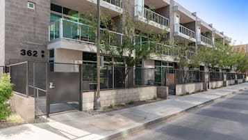 A modern multi-story building with balconies, a gated entrance, and a clear view of the street.