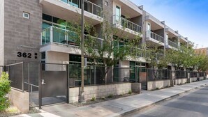 A modern multi-story building with balconies, a gated entrance, and a clear view of the street. - Jupiter's Studio Apartment with Pool!!! (Tempe)