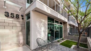A modern building with the number 358 on the facade, large glass windows, and a small outdoor seating area with metal chairs. - Jupiter's Studio Apartment with Pool!!! (Tempe)