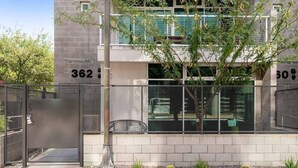 A modern building with a metal gate, numbered 362 and 50, and a tree in front.