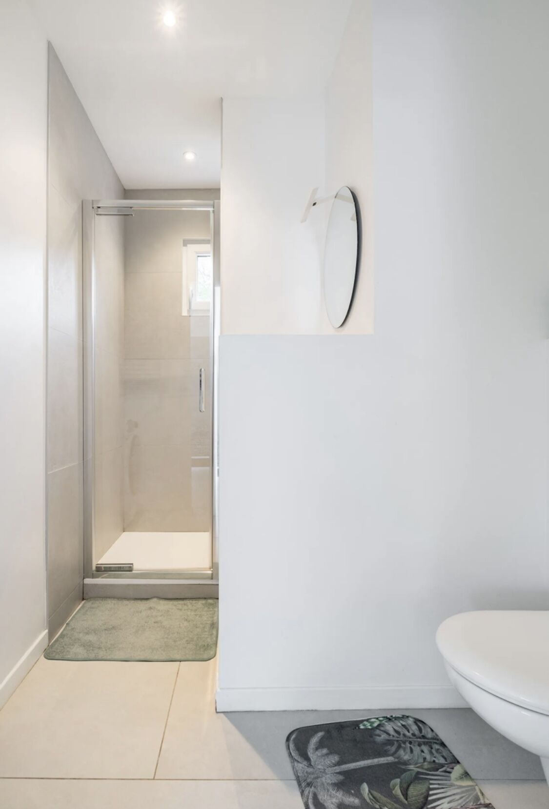 Un bagno moderno con un water, una doccia e uno specchio.