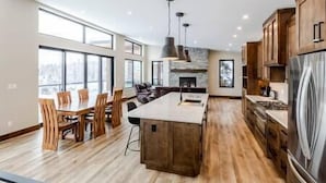A spacious kitchen with a large island, wooden cabinets, and a stone fireplace. - Luxury 4 BDR Home / Hot tub / Amazing Fireplace! (Fernie)